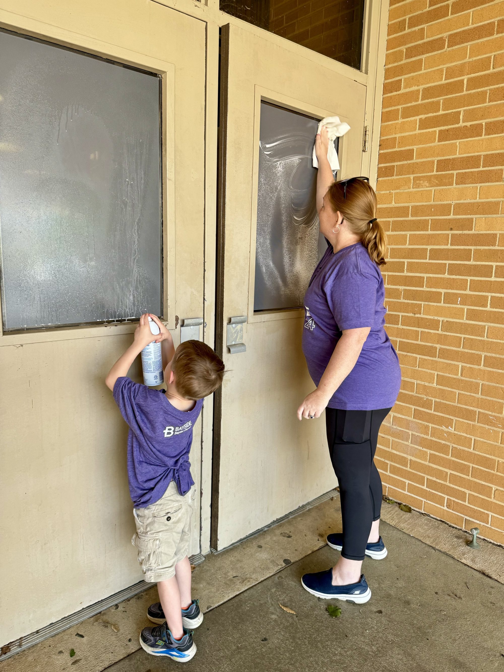A woman and student wipe down windows