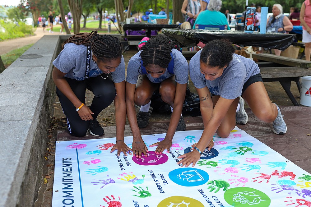 kids using handprints to make commitments poster at back to school bash