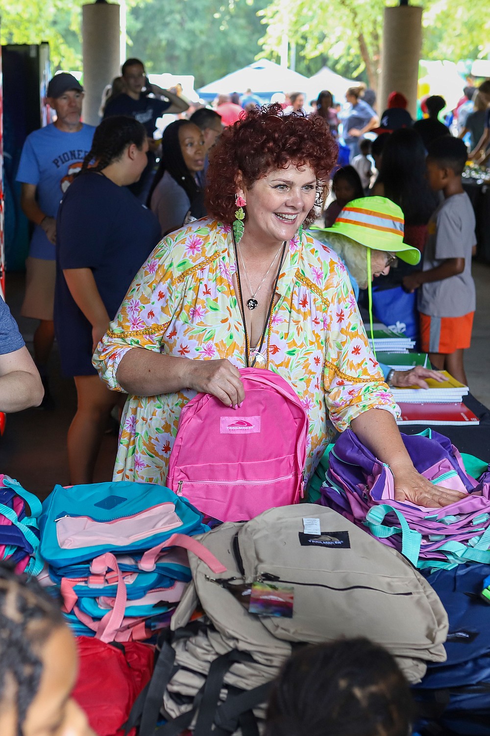 employee / volunteer helping hand out back packs at back to school bash