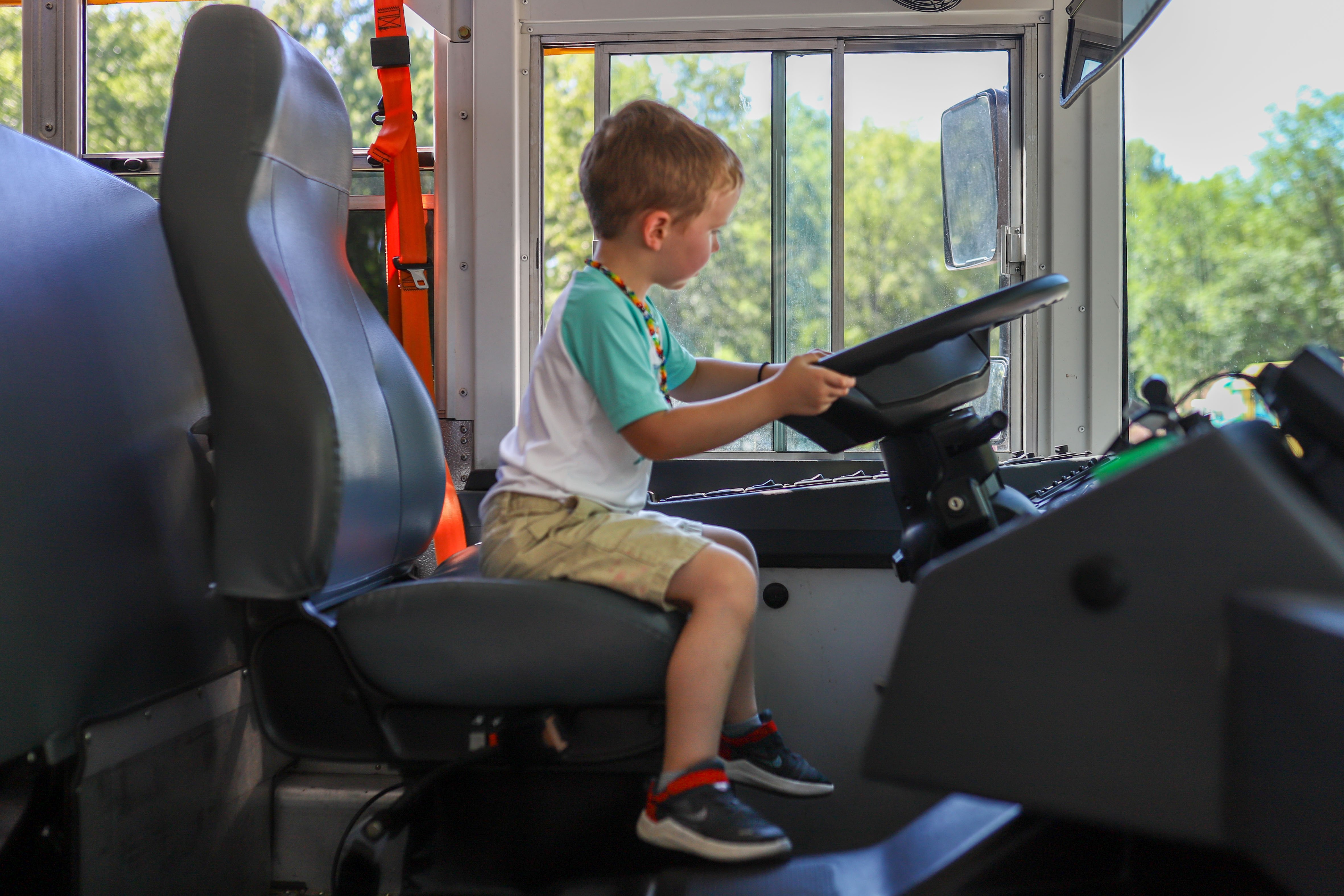 kid sitting in school bus driver seat