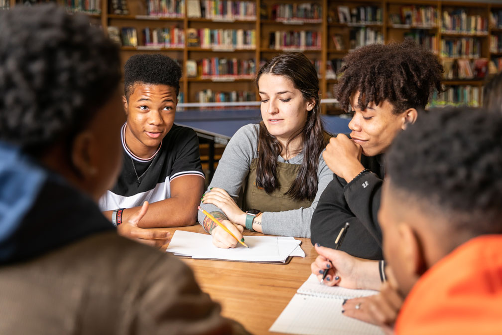 A teacher sits with students