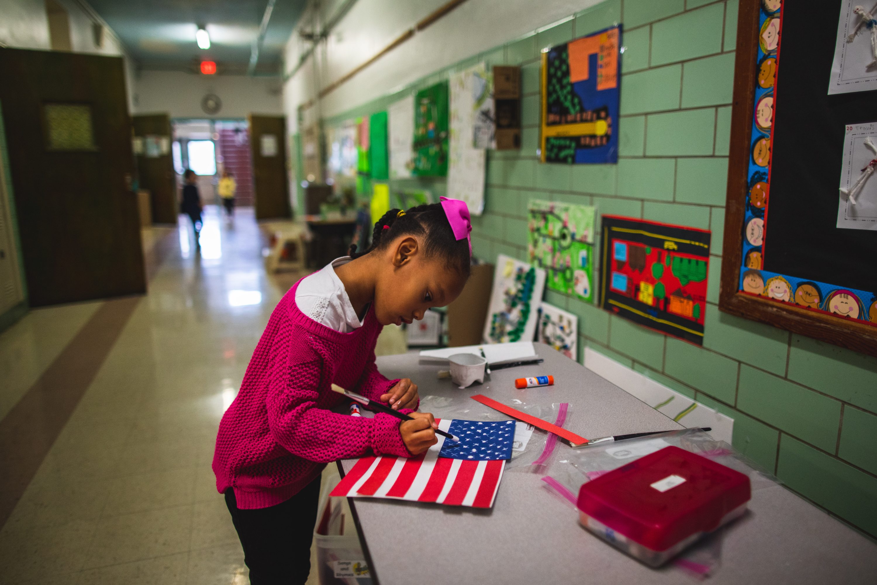 elementary student paints stars on flag art project in hallway