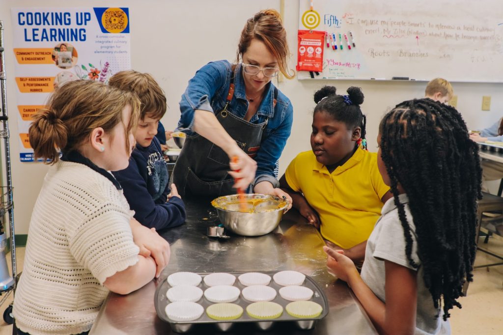A teacher helps students bake