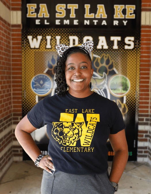 Dr. Jasmine Farrow Principal at east lake elementary in front of school with ears on in east lake shirt