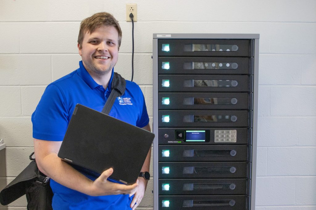 IT man in front of Tech tower at hunter middle holding laptop