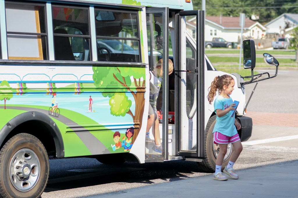 smiling students get off book bus
